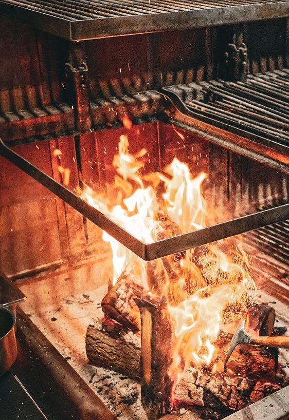 Flames rising from a wood-fired grill